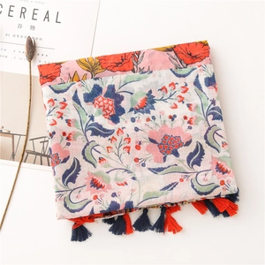 Detail shot of bohemian floral linen scarf with pink patterns and tassels on a table