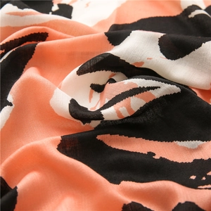 Close-up of orange pink and black abstract pattern on soft linen blend scarf fabric