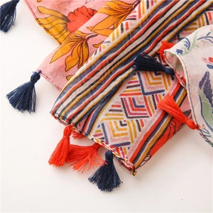 Close-up of cotton linen scarf with ethnic floral patterns and colorful tassel details