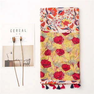 Detail of floral print cotton linen scarf with red tassels and boho ethnic patterns