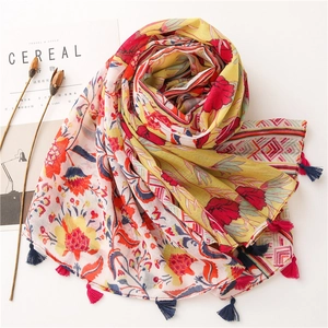 Detail of yellow cotton linen scarf with red floral print and colorful tassel edges