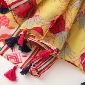 Close-up of lightweight cotton scarf with red floral patterns and colorful tassels