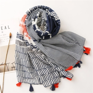 Detail of blue and white geometric cotton linen scarf with red and navy tassel charms