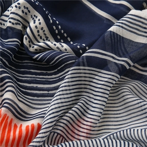 Close-up of navy blue and white striped cotton-linen scarf with orange detail