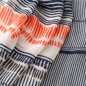 Detail of soft cotton-linen scarf showing navy blue and orange artistic stripes and texture