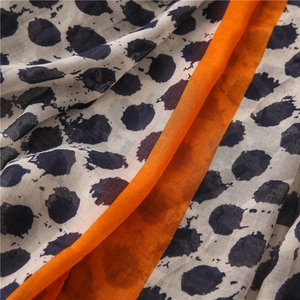 Gros plan détaillé du motif à pois sur l'écharpe en lin et coton avec bordure orange