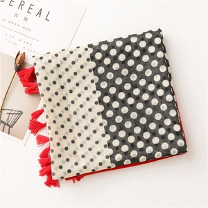 Detail of polka dot scarf with red tassels next to decorative magazine and flowers