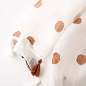 Detail of white cotton scarf with large brown polka dots and fringe tassel edges