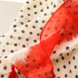 Detail of cotton linen scarf showing black polka dots and vibrant red fringe edges