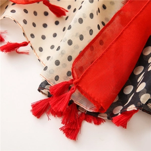 Macro shot of polka dot scarf fabric featuring vibrant red tassel fringe details
