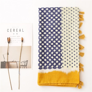 Detail of cotton linen scarf with blue polka dots and vibrant yellow fringe accents
