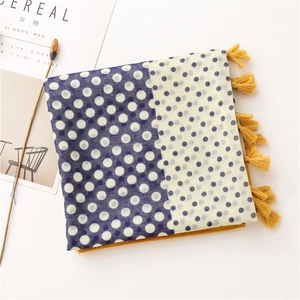 Detail of polka dot cotton linen scarf showing navy blue contrast and yellow tassels