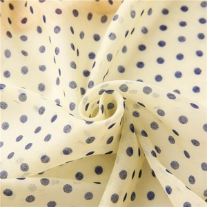 Macro detail of breathable cream cotton linen scarf featuring dark blue polka dot pattern