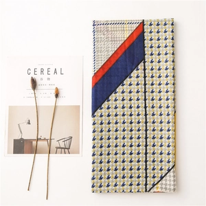 Flat lay of houndstooth patchwork scarf with geometric patterns on white background