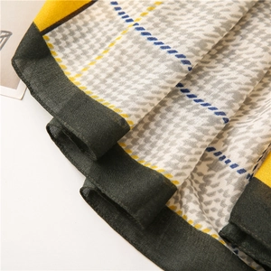 Detailed view of lightweight houndstooth scarf with yellow and dark green color blocks