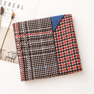 Detail of a folded houndstooth scarf with black white red and blue color block design