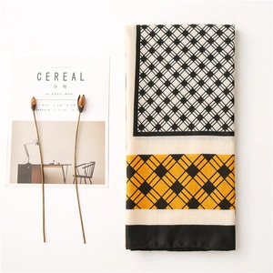 Detail of color-block plaid scarf with geometric patterns in black, white, and yellow