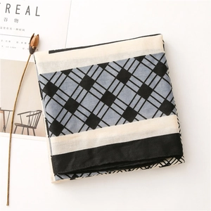 Flat lay of a blue plaid and striped cotton-linen scarf next to a decorative magazine