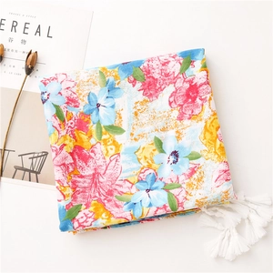 Detailed close-up of vibrant floral print scarf with soft white fringe and tassels