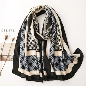 Close-up of lightweight geometric patchwork scarf with blue, black and white plaid patterns