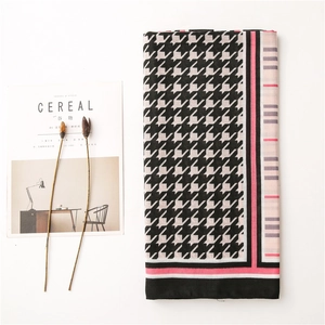 Detailed view of houndstooth cotton linen scarf with colorful striped edges on a magazine