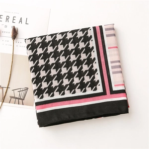 Detail of houndstooth cotton linen shawl with pink trim next to a lifestyle magazine
