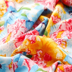 Floral twill cotton scarf featuring bright yellow and blue blossoms with soft draped texture