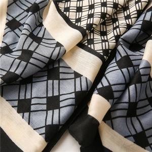 Close-up of geometric pattern scarf showing light blue and beige woven fabric texture