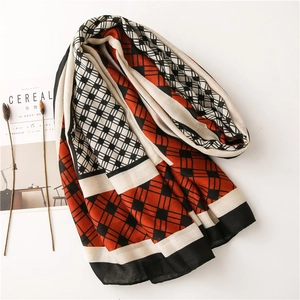 Flat lay of cotton linen scarf with geometric orange, black, and white plaid patterns