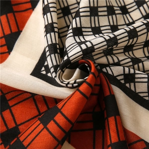 Close-up of geometric pattern scarf showing vibrant orange and black woven fabric texture