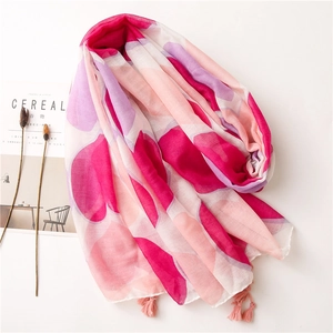 Dettaglio di sciarpa rosa con motivo a cuori e delicate frange su sfondo bianco