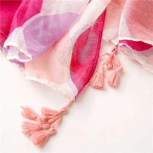 Dettaglio del tessuto in viscosa della sciarpa con nappe rosa e motivi geometrici vivaci