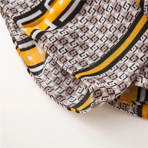Detail of soft scarf showing mustard and black geometric patterns and fine stitching
