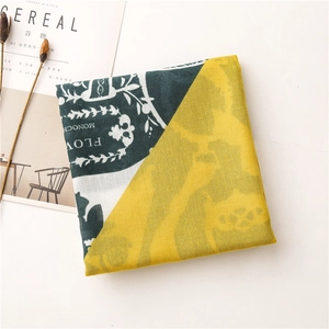 Detail view of vintage scarves with yellow and green baroque pattern near a magazine
