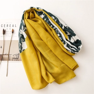 Detail of yellow and dark green scarf with floral prints and soft fabric texture