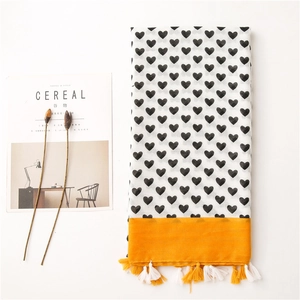 Detailed view of white cotton linen scarf with black heart prints and yellow tassels
