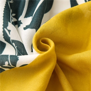Macro shot of ginger yellow and printed cotton blend scarf fabric with woven texture