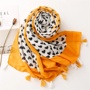 Detailed shot of yellow and white heart print scarf with decorative tassel edges