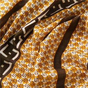 Close-up of retro geometric diamond patterns on soft yellow and black scarf fabric