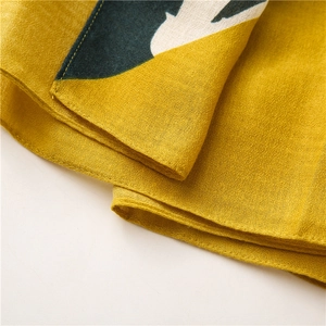 Close-up of fine hemmed edges and yellow geometric patterns on long scarf fabric