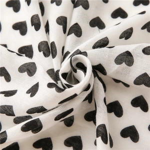 Detail of soft cotton linen fabric featuring a classic black heart print on a white base