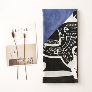 Flat lay of folded scarf with geometric blue and black panels next to Cereal magazine