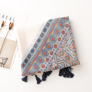 Détail d'une écharpe bohème à imprimé géométrique avec pompons bleus et tissu doux lin-coton