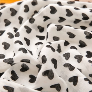 Detailed macro view of white cotton-linen fabric with black heart patterns and woven texture