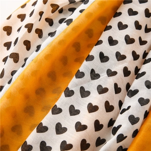 Detail of soft cotton linen scarf with yellow white stripes and black heart patterns