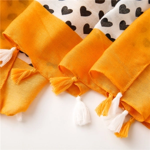Close-up of yellow herringbone border with black heart print and fringed tassels