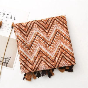 Detail of bohemian zigzag pattern scarf with tassels next to a decorative magazine