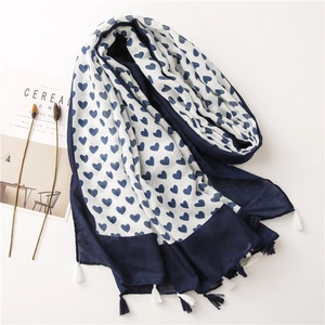 Detail of navy blue cotton linen scarf with heart patterns and fringe tassels
