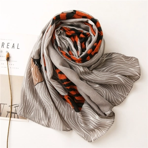 Détail d'une écharpe grise à lignes ondulées blanches et motif zèbre orange vif