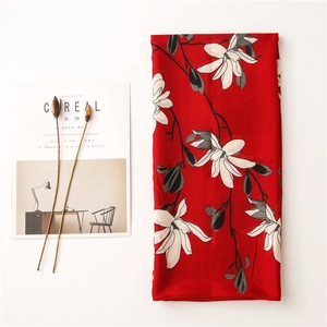 Detail of red floral scarf featuring white magnolia prints and minimalist linen texture